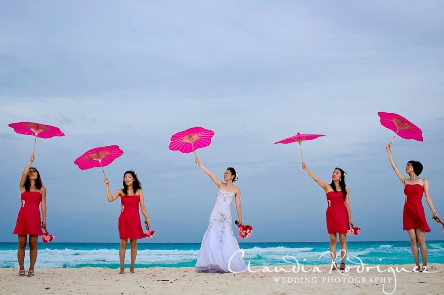  bride and bridesmaids on the beach with umbrellas 