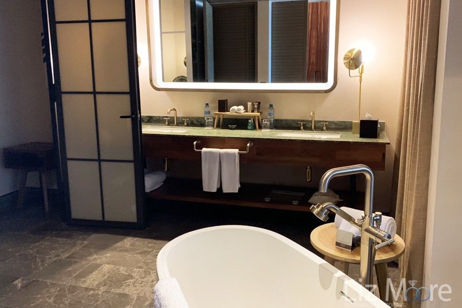 Main bathroom with double sink vanity's large white soaker tub and beautiful colored marble flooring