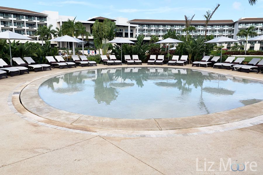 Waiting pool area surrounded by beach loungers and white umbrella's