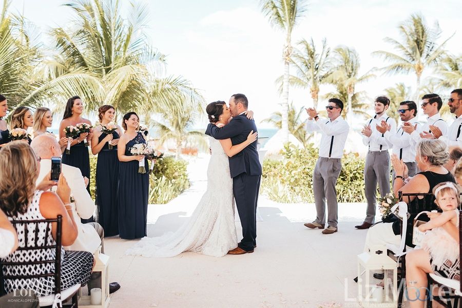 Wedding ceremony on the beach with the bridesmaids grooms and wedding couple kissing