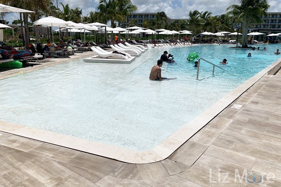 Main swimming pool area with lounge chairs and umbrellas and shallow waiting pool area