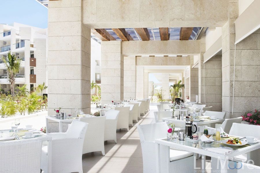 restaurant outdoor area With white to chairs and tables set up with a view of those Gardens and grounds