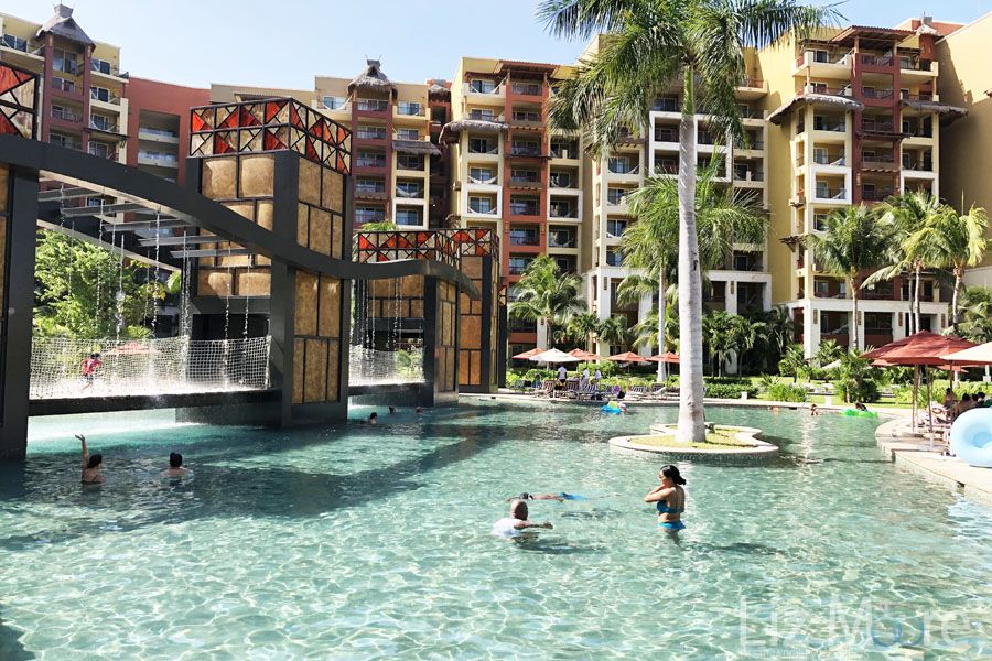 main pool area With gas swimming and surrounded by palm trees and room buildings