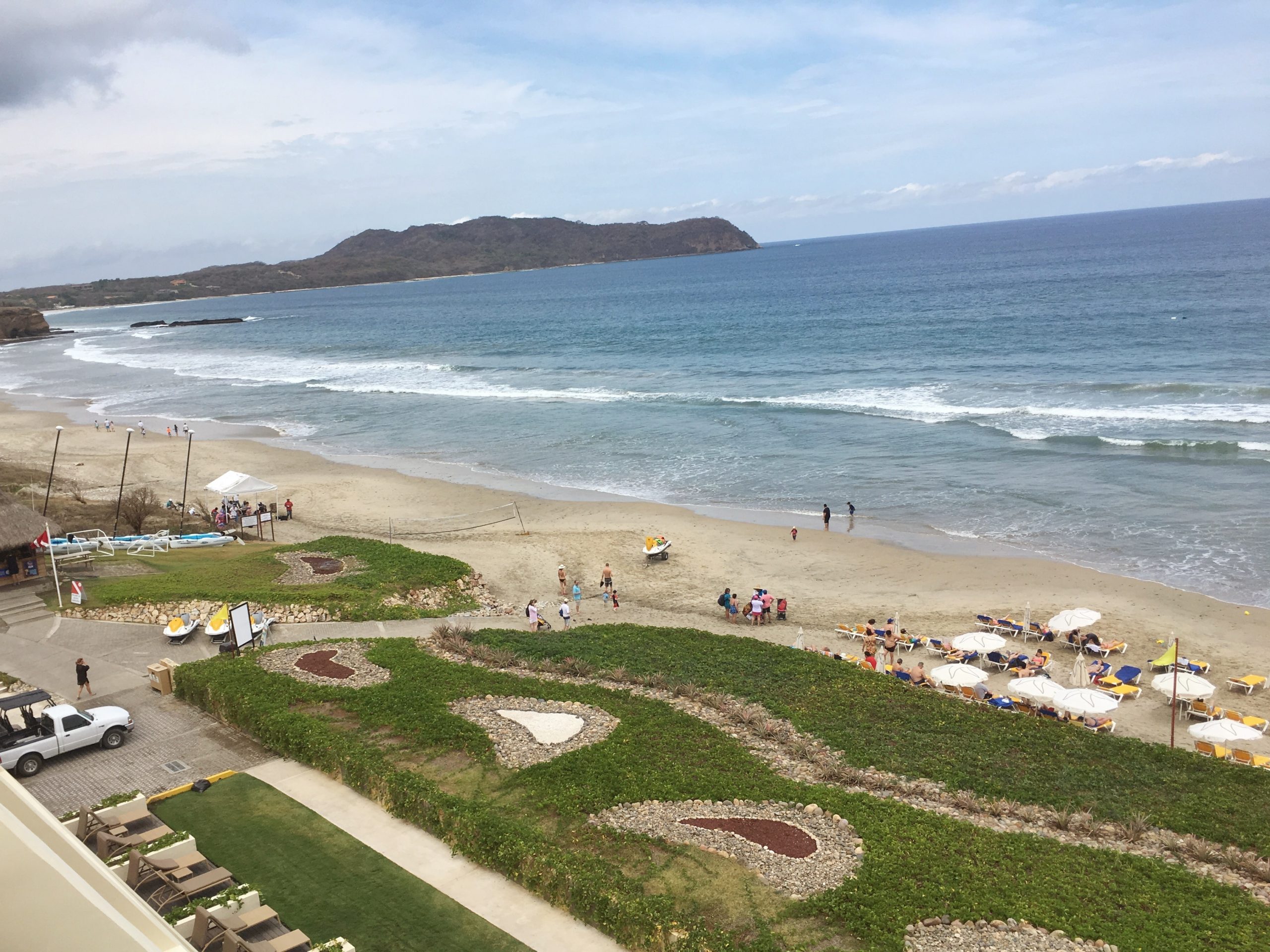aerial view of lawns and beach as well as ocean and surrounding mountains