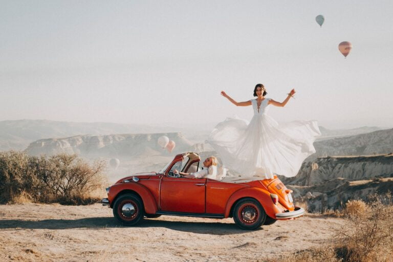 Bride on top of car overlooking beautiful scenic mountains